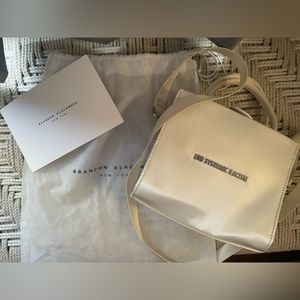 Cream satin End Systemic Racism Brandon Blackwood purse with dust bag.